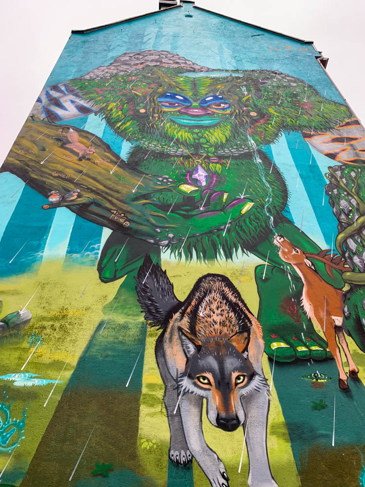 Street Art in Bergen an Fassade. Die gesamte Hauswand ist von einem Waldtroll mit einem Wolf und Reh ziert das Haus.