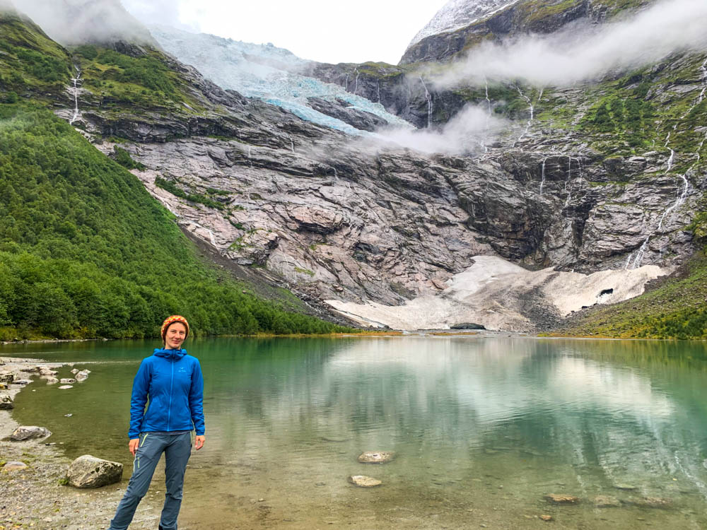 Melanie steht am Ufer des Gletschersee vom Bøyabreen Gletscher. Der Gletscher hängt hinter ihr am Fels (Hängegletscher). Norwegen Bergpässe, Fjorde und Wasserfälle