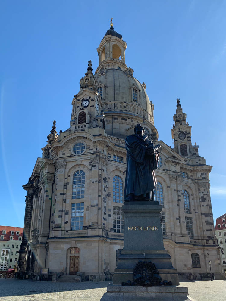 Frauenkirche mit Luther-Denkmal. Im Hintergrund ist der blaue Himmel zu sehen.