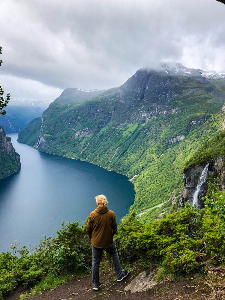 Julian steht an einem Aussichtspunkt am Geiranger Fjord. Norwegen Bergpässe, Fjorde und Wasserfälle
