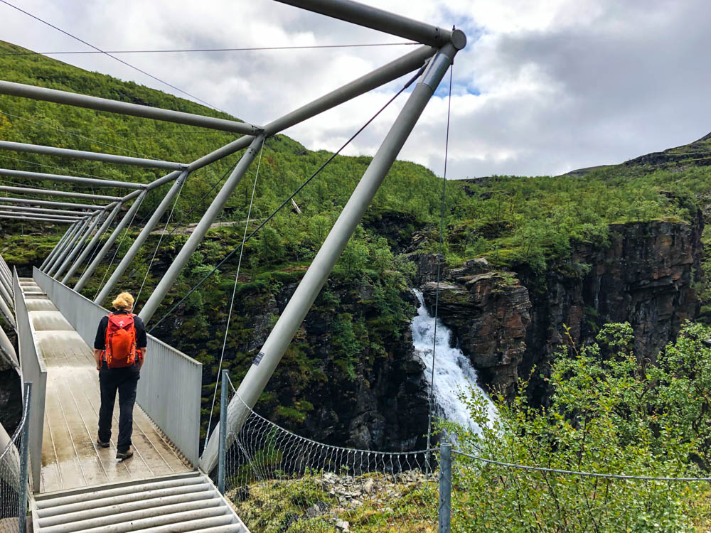 Julian läuft auf Brücke mit Blick auf Gorzifossen Wasserfall, Wanderung Gorsabrua. Alta bis zu den Lofoten