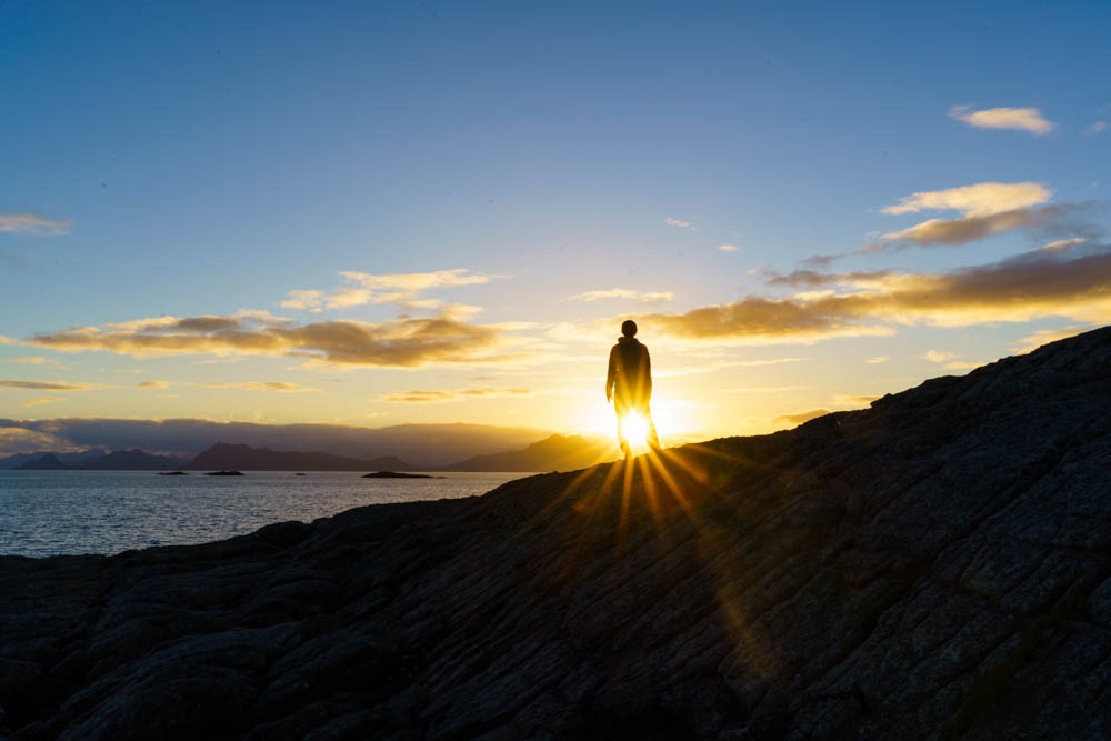 Sonnenuntergang auf Lofoten in Henningsvær. Melanie mit Sonnenstern blickt auf Atlantik. Lofoten - Alpen im Meer