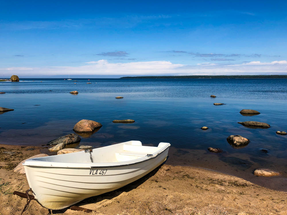Ein Ruderboot an Land. Aus der Ostsee schauen vereinzelt Steine.