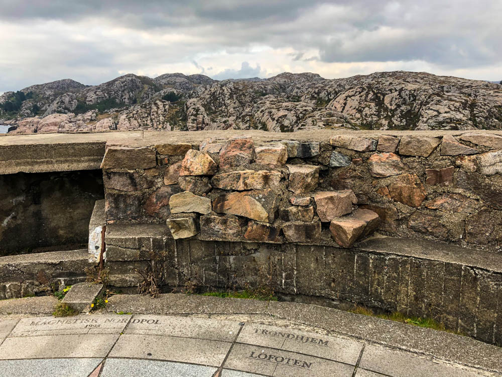 Von einem ehemaligen Bunker schaut man in die Ferne auf den Fjell. Auf dem Boden stehen verschiedene Ziele in alle Himmelsrichtungen. Der Blick geht Richtung Lofoten.