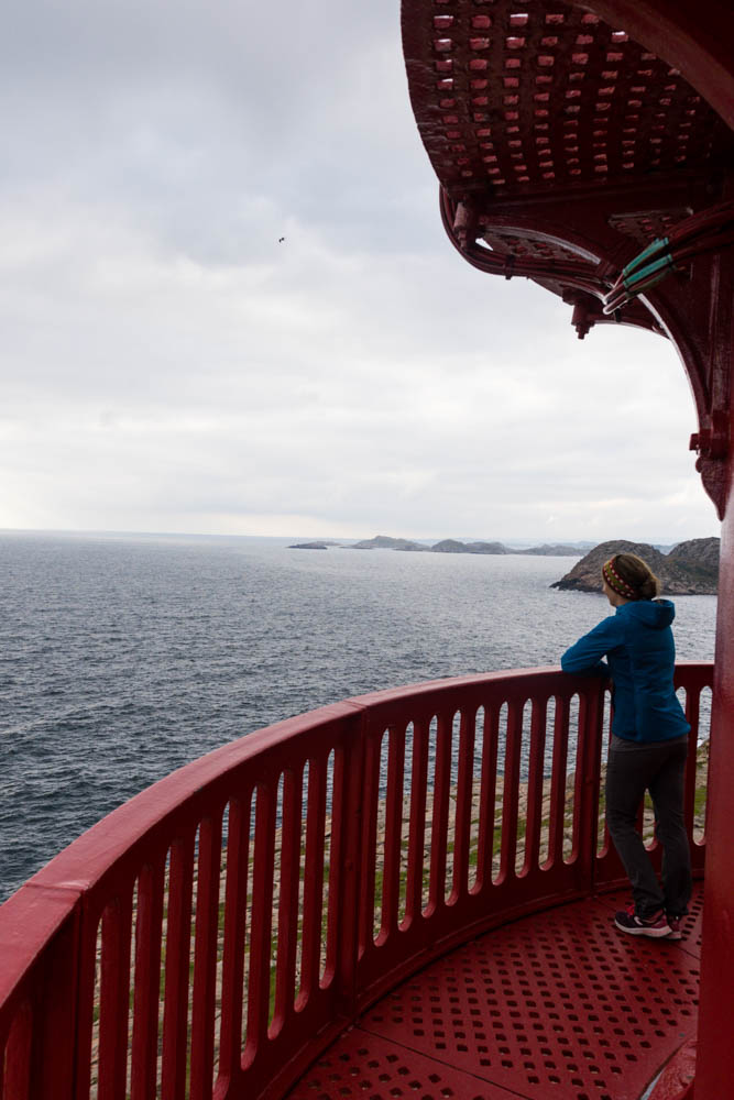 Melanie steht auf dem Leuchtturm Lindesnes Fyr und schaut auf die Nordsee. Am Horizont sieht man die Küstenlinie von Norwegen. Tour bis nach Kristiansand