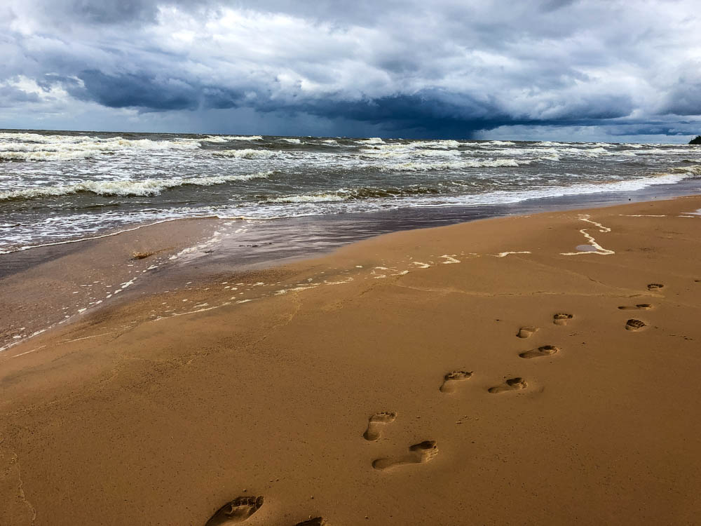 Melanies und Julians Fußspuren im Strand an der Ostsee. Der Himmel ist düster und es zeiht eine Unwetter herauf. Tausche Stadtleben gegen Natur pur