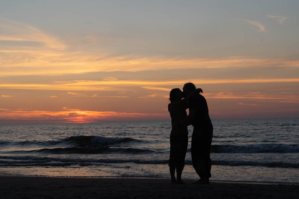 Melanie und Julian küssen sich beim Sonnenuntergang an der Ostsee.