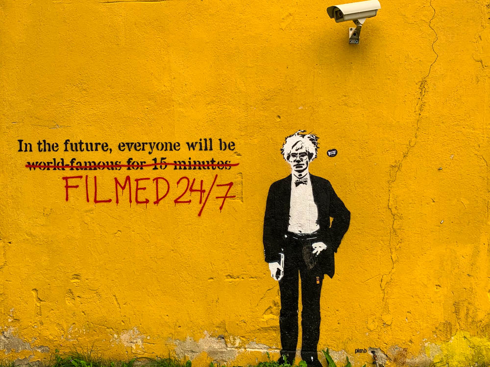 Streetart in Tallinns Künstlerviertel. Ein Mann steht unter einer Kamera. Aus dem berühmten Satz:"in the future, everyone will be world famous for 15 minutes.", wurde "In the future, everyone will be filmed 24/7!" gemacht.