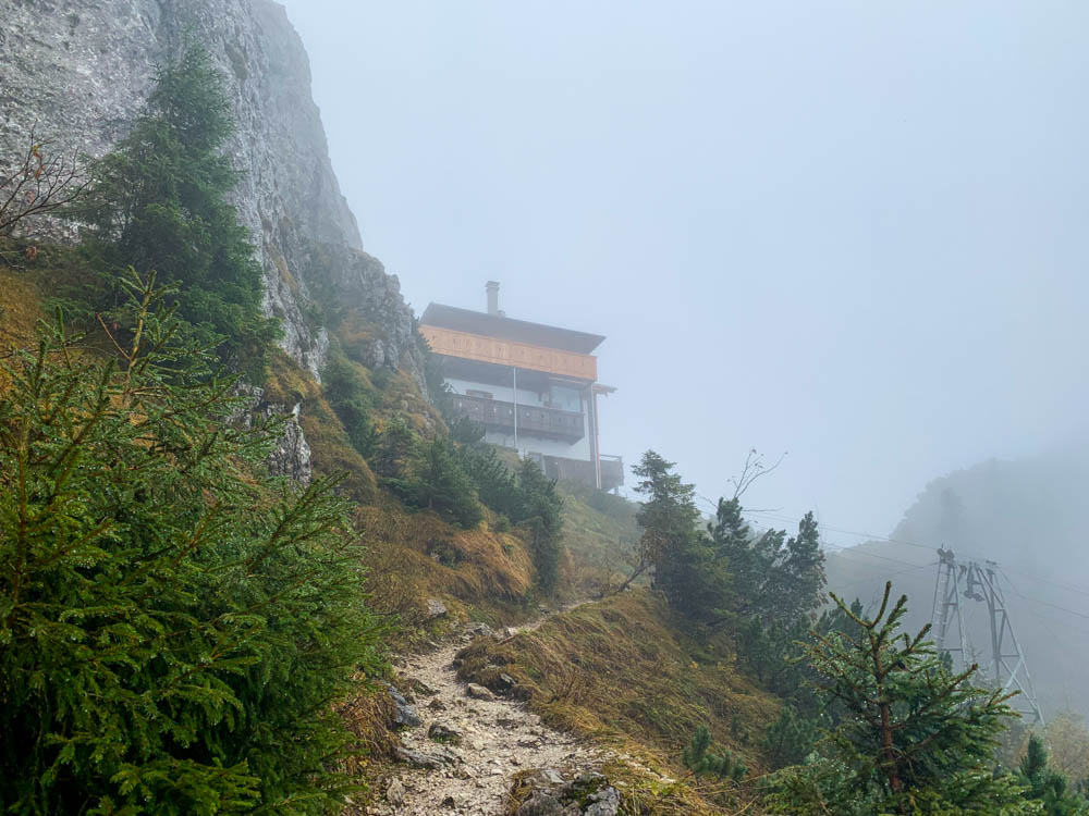 Deutsche Alpen - Die Tegernseer Hütte ist am Horizont leicht zu sehen. Die Wolken hängen dicht über der Hütte und den umliegenden Gipfeln.