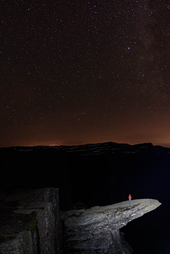 Norwegen, Trolltunga bei Nacht mit Sternenhimmel. Melanie steht auf Trolltunga