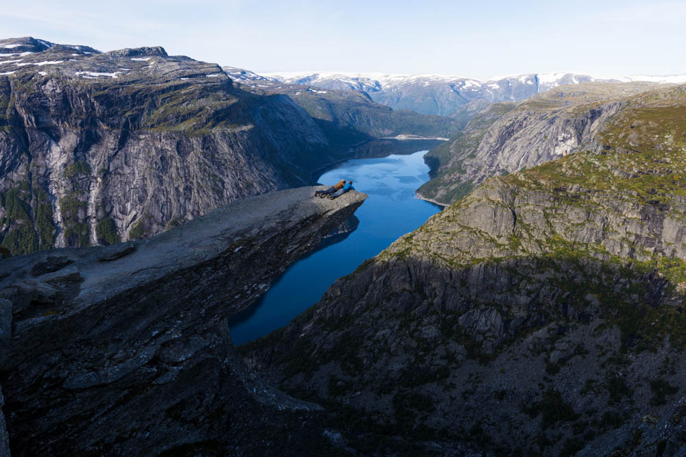 Norwegen, Melanie und Julian liegen auf Trolltunga und schauen über Kante in die Tiefe