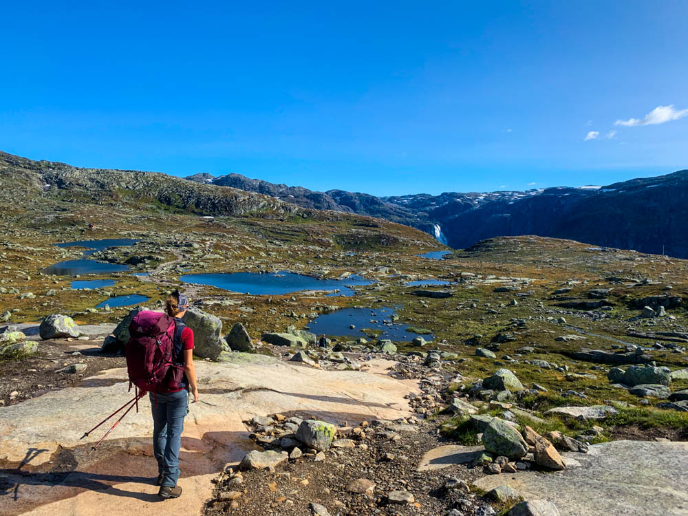 Norwegen, Melanie mit großem Rucksack auf dem Weg zu Trolltunga. Blauer Himmel