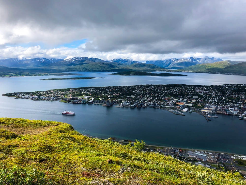 Blick auf Tromsø in Norwegen vom Hausberg Storsteinen. Eine Fähre der Hurtigruten läuft gerade ein.