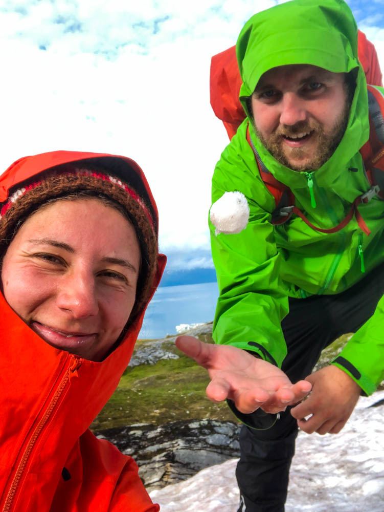Selfie von Melanie und Julian wie sie auf einem Altschneefeld einen Schneeball in die Luft werfen.