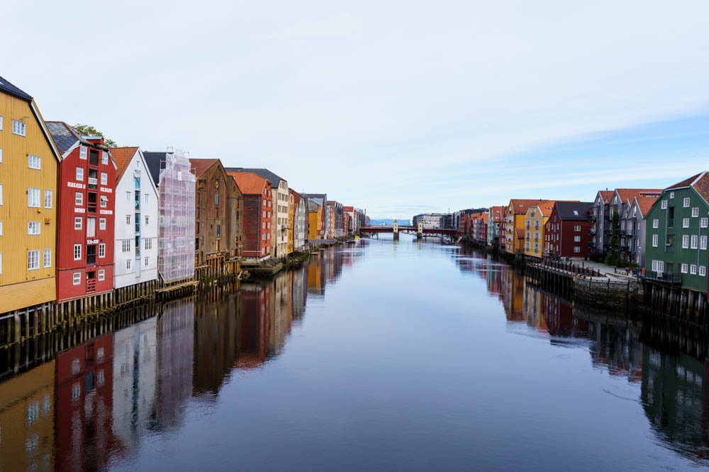 Bunte Häuser auf Stelzen stehen rechts und links am Fluss in Trondheim