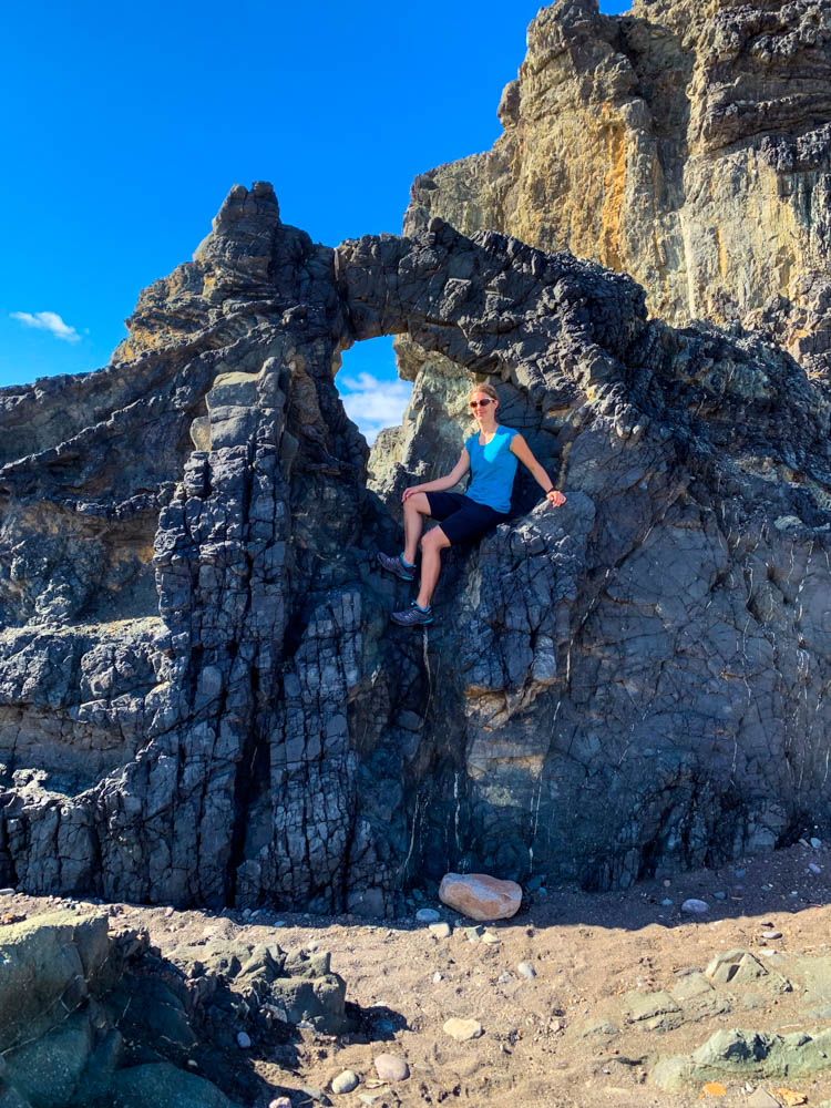 Melanie sitzt in einem kleinen Felsentor. Erkundungstouren auf Fuerteventura