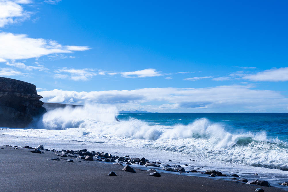 Wellen rollen an den Strand von Ajuy. Diese brechen und die Gischt spritzt stark.
