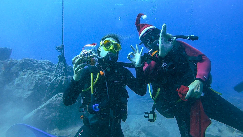 Melanie bekommt unter Wasser vom Nikolaus ein Geschenk überreicht. Beide geben das OK Zeichen. Wassersport im Süden von Fuerteventura, hier Tauchen