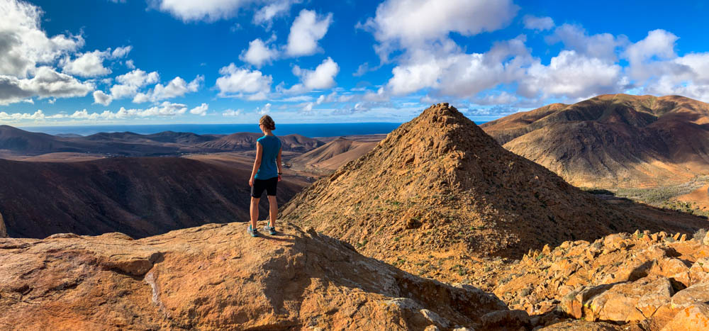 Melanie steht vor Hügellandschaft und blickt in die Ferne. Erkundungstouren auf Fuerteventura