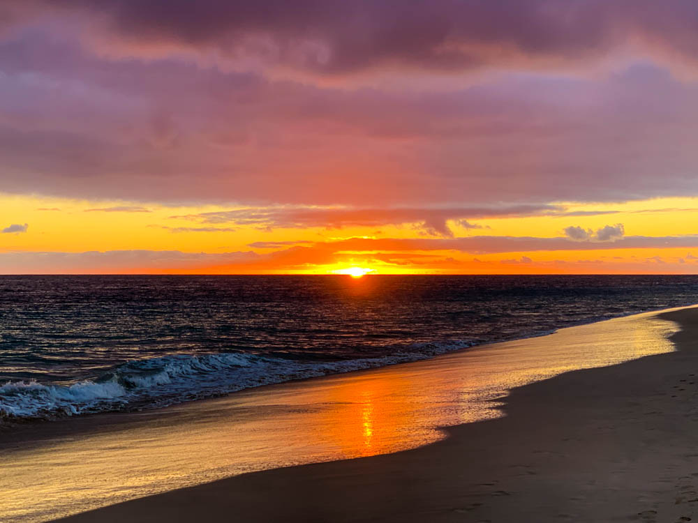 Sonnenuntergang am Strand von Jandia. Der Himmel hat ein Farbenspiel von Gelb, Orange und Lila angenommen.