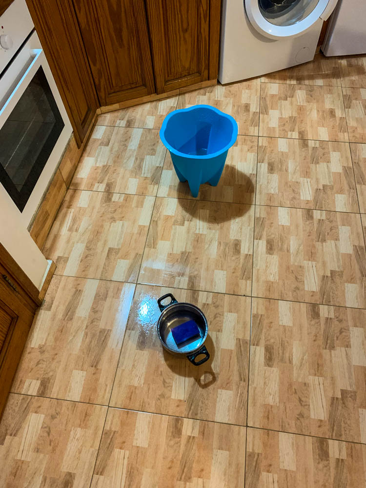 In der Küche stehen verteilt ein Mülleimer und ein Topf um das Wasser welches von der Decke tropft aufzufangen.
