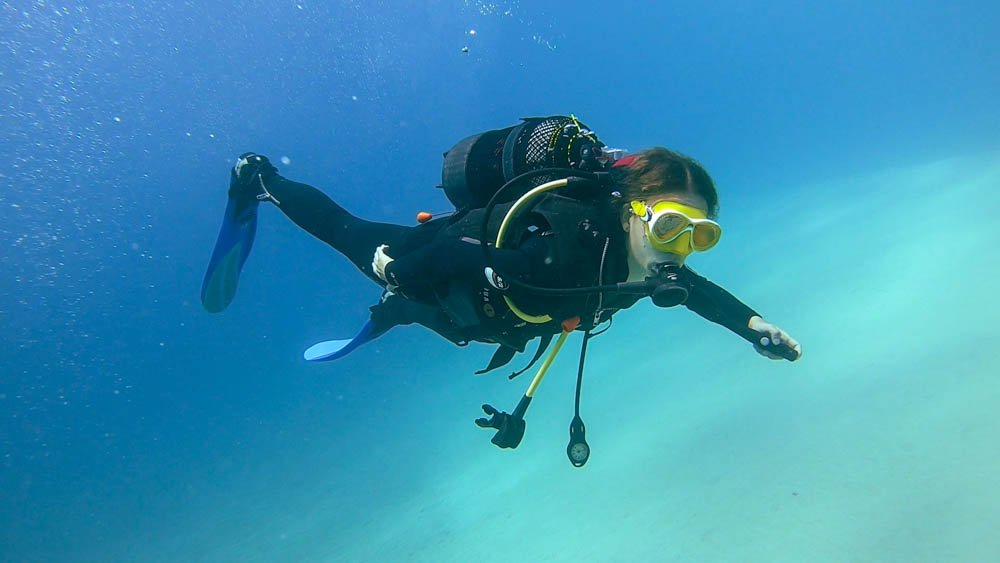 Melanie taucht in blauem Wasser. Unter ihr ist der weiße Sand vom Meeresgrund zu sehen. Wassersport im Süden von Fuerteventura