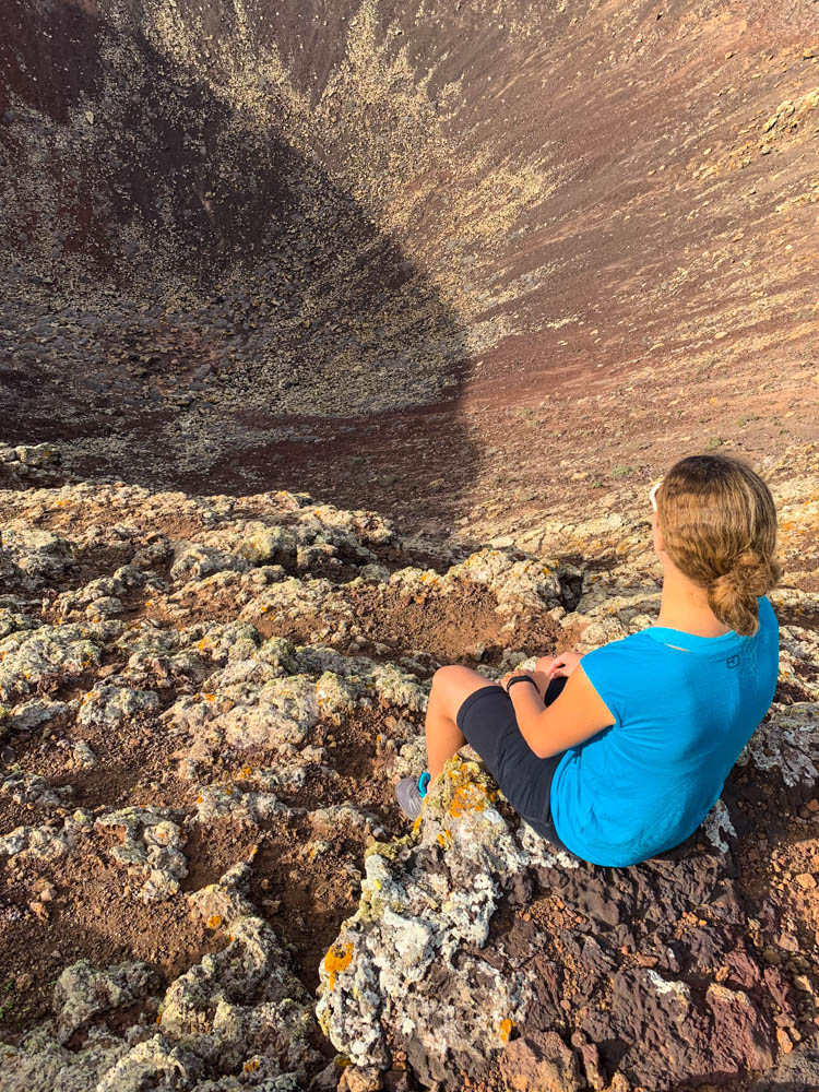 Melanie sitzt am Krater von Calderón Hondo und schaut in en tiefen Kraterschlund.