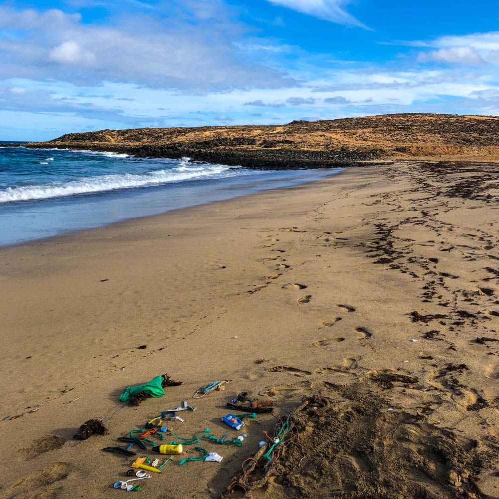 Mit Plastikmüll wurde Happy New Year in den Sand "geschrieben". Es ist zudem der gesäuberte Strand mit auf dem Bild. Frohes Neues - Happy New Year - Feliz Año Nuevo