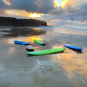 Wassersport im Süden von Fuerteventura: Es liegen mehrere Surfbretter auf dem Sand direkt am Atlantik. Sonnenuntergang