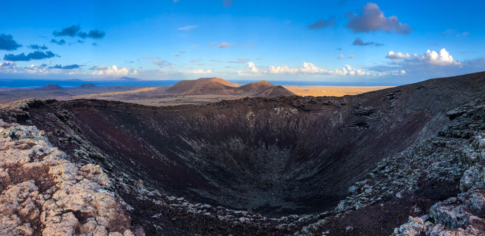 Panorama von Vulkan Calderon Hondo. Es ist der komplette Krater zu sehen. Am Horizont sieht man den Atlantik sowie Lanzarote.