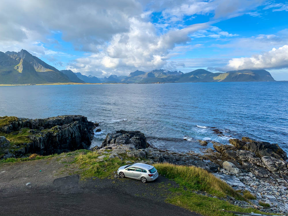 Mini-Camper Astrarix steht direkt neben dem Atlantik in Norwegen. Im Hintergrund sind Berge der Lofoten zu sehen und der Himmel ist leicht bewölkt.