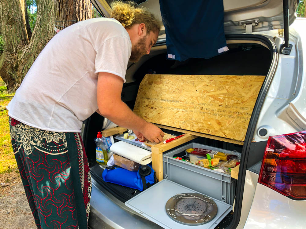 Julian bereitet gerade Essen in der Küche im Mini-Camper Astrarix vor.