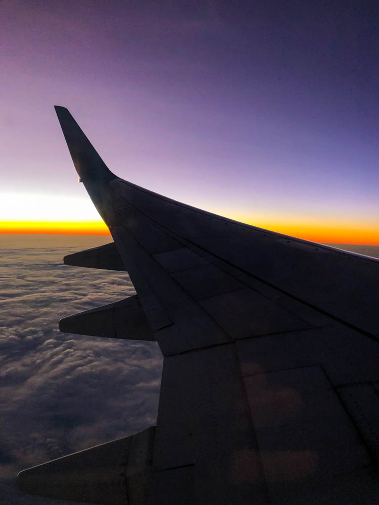 Blick aus Flugzeugfenster auf Flügel des Flugzeugs. Die Sonne ist untergegangen und der Horizont ist orange verfärbt. Unsere Zeit auf Fuerteventura geht zu Ende