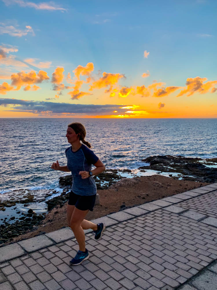 Melanie beim Joggen an der Atlantikküste. Am Horizont geht gerade die Sonne über dem Atlantik auf.