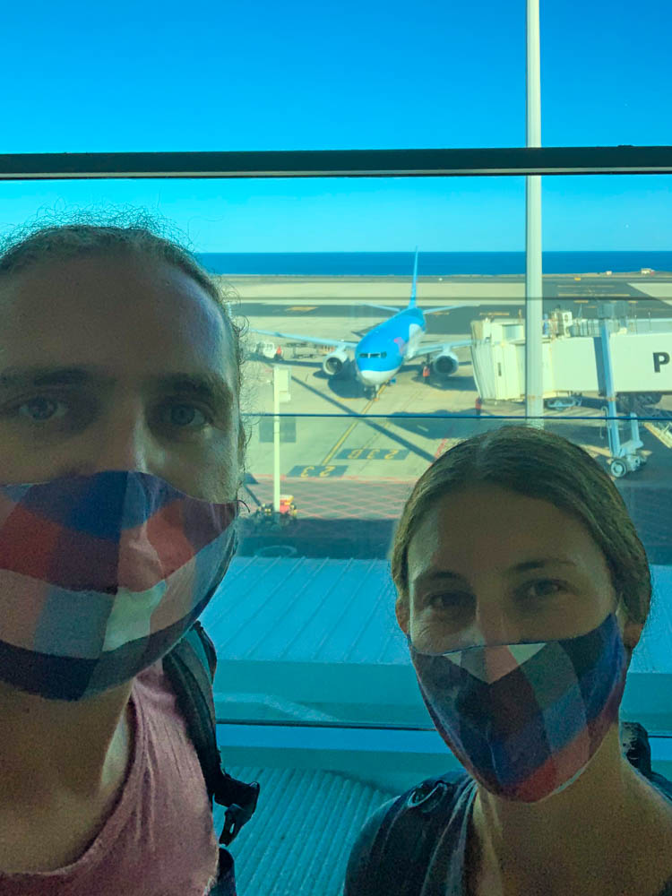 Selfie von Melanie und Julian vom Flughafen. Im Hintergrund durch die Scheiben ist ein Flugzeug zu sehen. Unsere Zeit auf Fuerteventura geht zu Ende