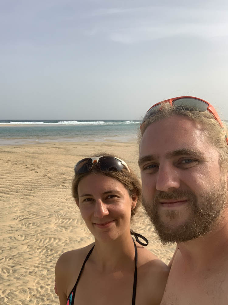 Selfie von Melanie und Julian am Sotavento Beach. Es ist der weiße Sand, der Atlantik sowie im Hintergrund der Calima zu sehen.