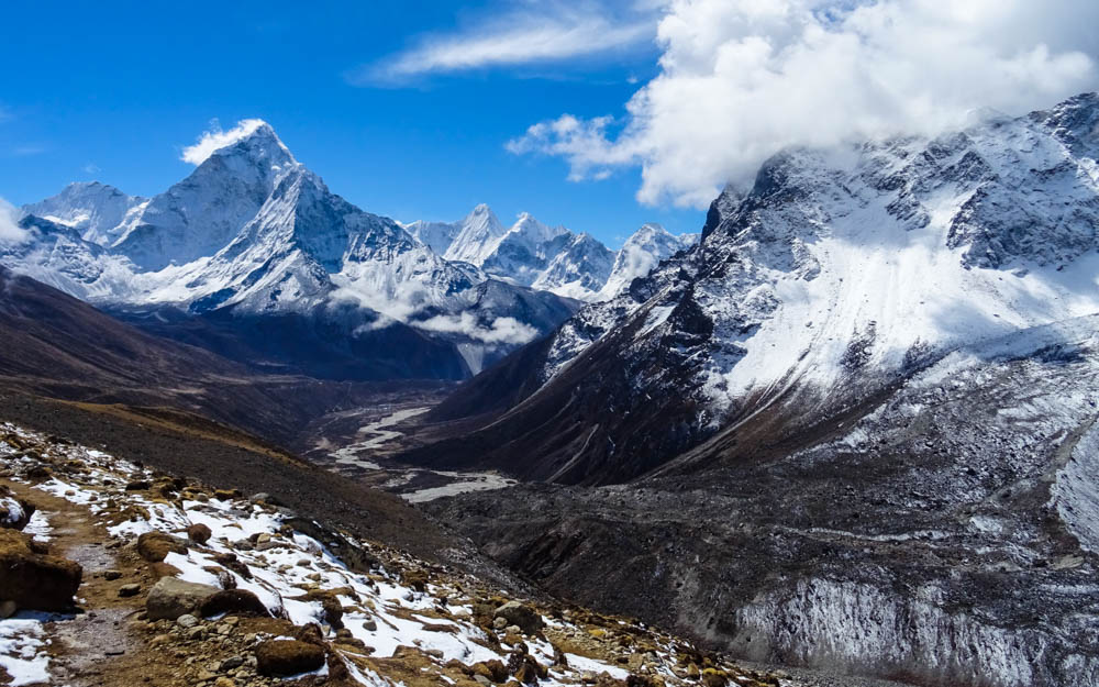 Blick in ein Tal im Himalaya Gebirge. Hinten links ist der Ama Dablam zu sehen, der von schneebedeckten Bergen umgeben ist. Fortsetzung Trekking Mount Everest Region