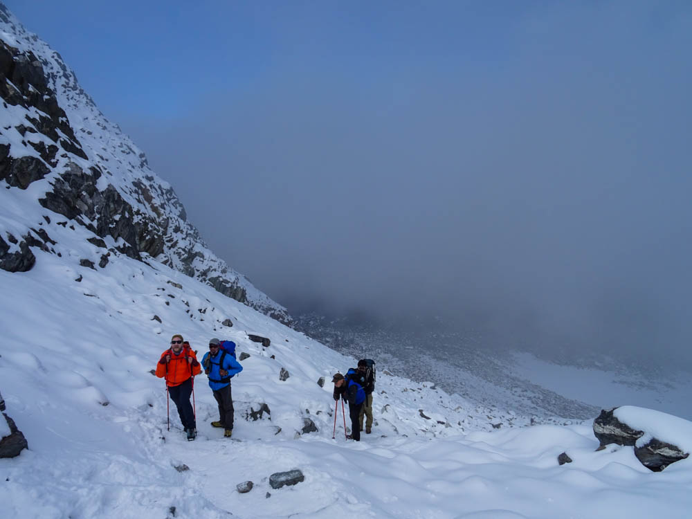 Schneebedeckter Cho La Pass. Der Himmel ist voller Nebel, Julian und Guide Keshar kämpfen sich durch den Schnee. Fortsetzung Trekking Mount Everest Region