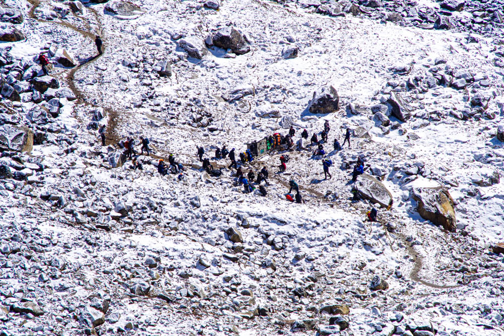 Es sind ein paar Menschen auf dem Weg zum Mount Everest Base Camp zu sehen. Es liegt überall Schnee. Trekking Fortsetzung