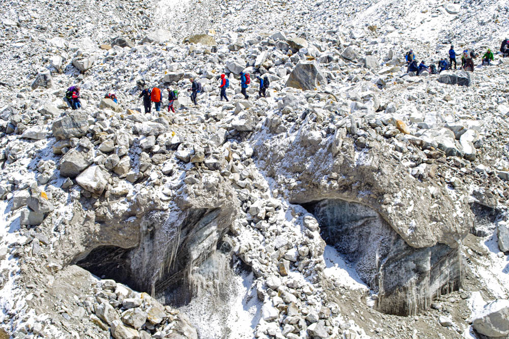 Es sind ein paar Menschen auf dem Weg zum Mount Everest Base Camp zu sehen. Es liegt überall Schnee und man sieht den Gletscher gut. Trekking Fortsetzung