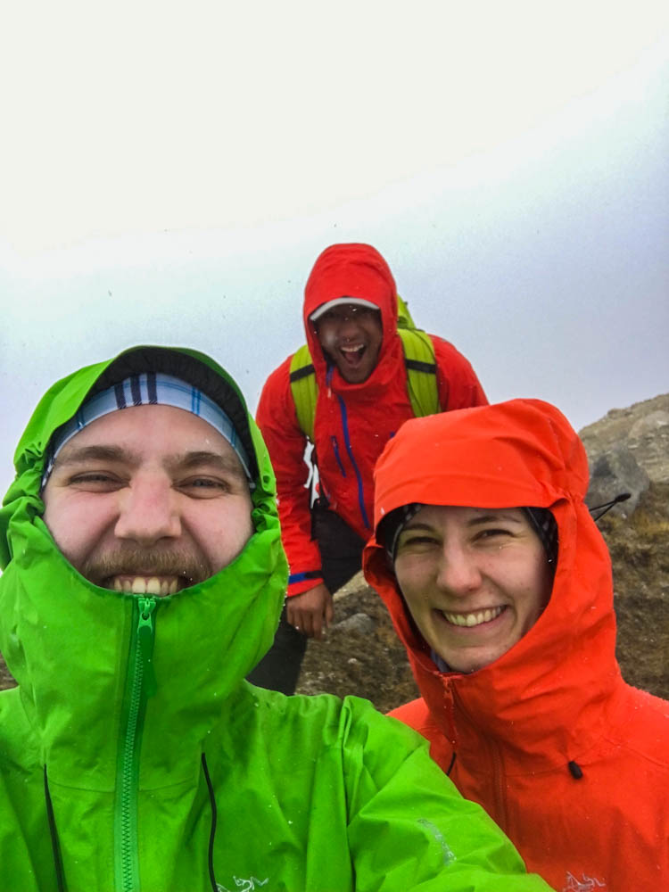 Selfie von Melanie, Julian und Guide Keshar bei Trekking Nepal. Alle drei lachen und spaßen herum. Sie stehen mitten im Nebel und es schneit leicht.