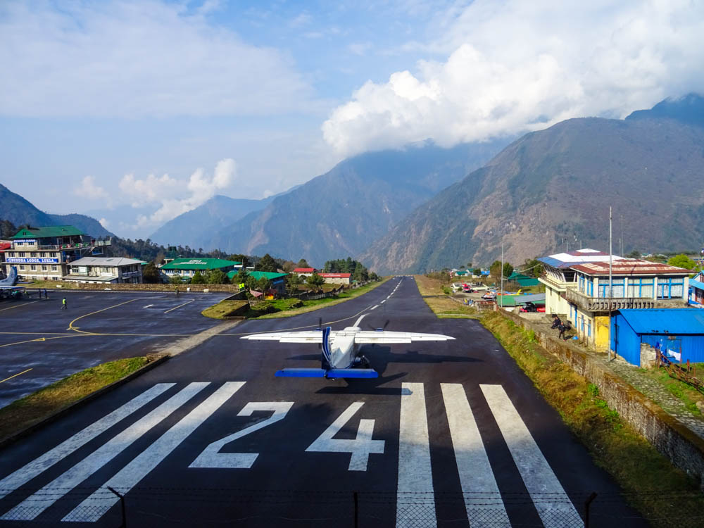 Ein Flugzeuf steht auf der Landebahn von Lukla in Nepal und macht sich Startbereit. Rechts im Bild sieht man den kleinen Tower.