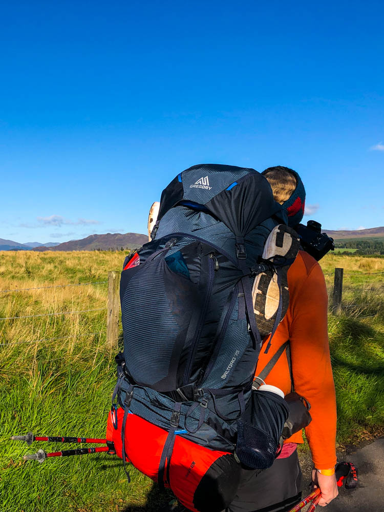 Packliste Trekking Weltreise - Backpack Julian - Julian steht mit seinem Backpack an einem Aussichtspunkt und schaut in die Ferne.