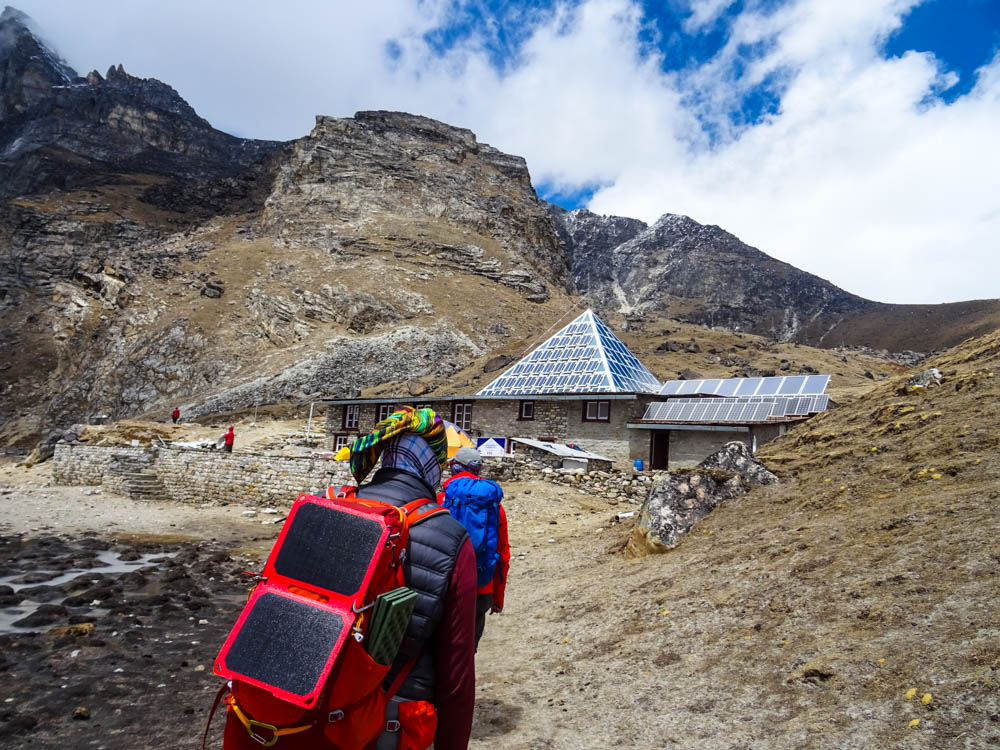 Lodge Pyramid mit umliegender Landschaft. Der Himmel ist leicht bewölkt, Julian läuft in Richtung Hütte.