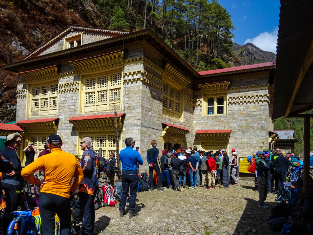 Viele Menschen stehen vor dem Kassenhaus des Sagarmatha Nationalpark Zentrums. Jdeder wartet bis der endlich an die Reihe kommt. auf dem Vorplatz stehen viele Trekker die warten, dass ihre Guides oder Begleiter die Tickets lösen