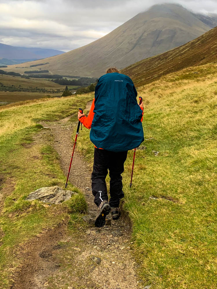 Packliste Trekking - Melanie läuft mit Backpack und Regencover darüber durch die Highlands in Schottland