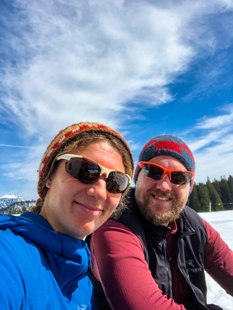 Selfie von Melanie und Julian. Im Hintergrund ist etwas Schnee zu sehen, der Himmel ist leicht bewölkt.