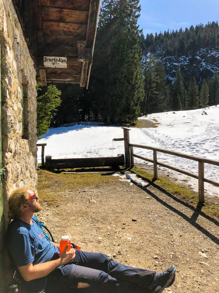 Julian sitzt vor der Orterer Hütte und lässt die Sonne in den Alpen auf sich scheinen.