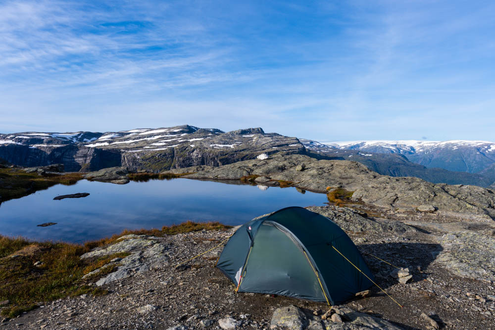 Zelt steht bei Trekkingtour zur Trolltunga vor einem kleinen See. Dahinter bergige, norwegische Landschaft. Zelt Teil der Packliste, welche vorgestellt wird.