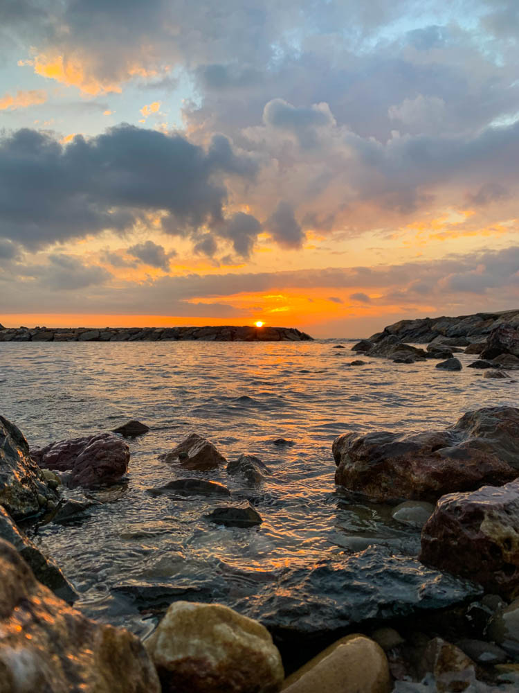 Sonnenuntergang am Mittelmeer der Costa Brava in Spanien. Am Himmel sind einige Wolken die den orangenen Ton der untergehenden Sonne angenommen haben. Die Sonne versinkt in wenigen Minuten im Meer und glüht im schönsten orange.